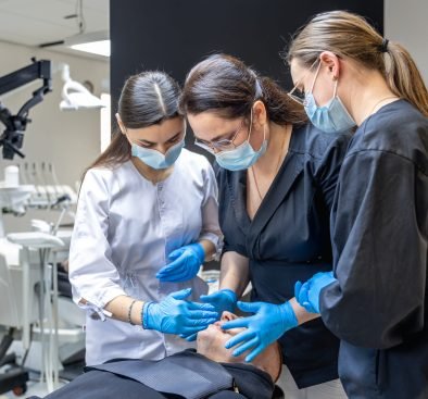 Team of female dentists treating patient's teeth. Visit to the dentist. Dentistry. High quality photo. Dentists in rubber gloves and medical masks on their faces. Dental office.